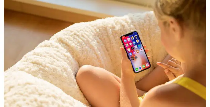 A woman sitting on the couch holding her phone.