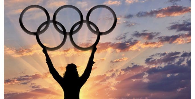 A person holding up olympic rings in the air.